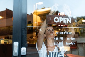 woman hanging open sign on business door