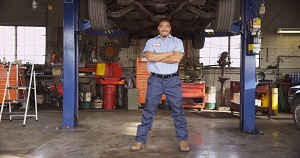 mechanic standing with arms crossed smiling at camera