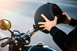 person sitting on motorcycle holding helmet